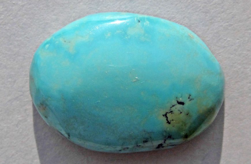 turquoise stone cabochon on beige background to illustrate blue turquoise