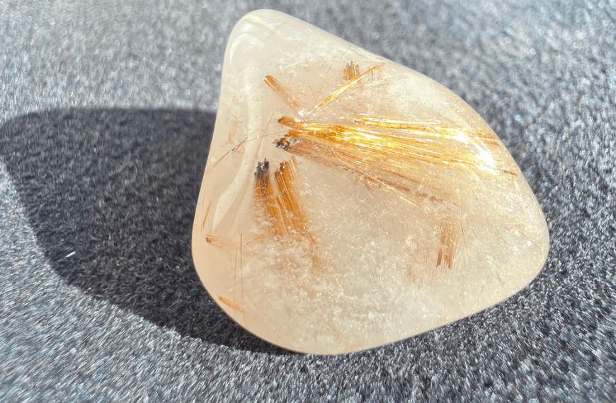 rutile-inclusion quartz stone showing its texture as a rolled stone on a natural background to illustrate inclusion quartz.