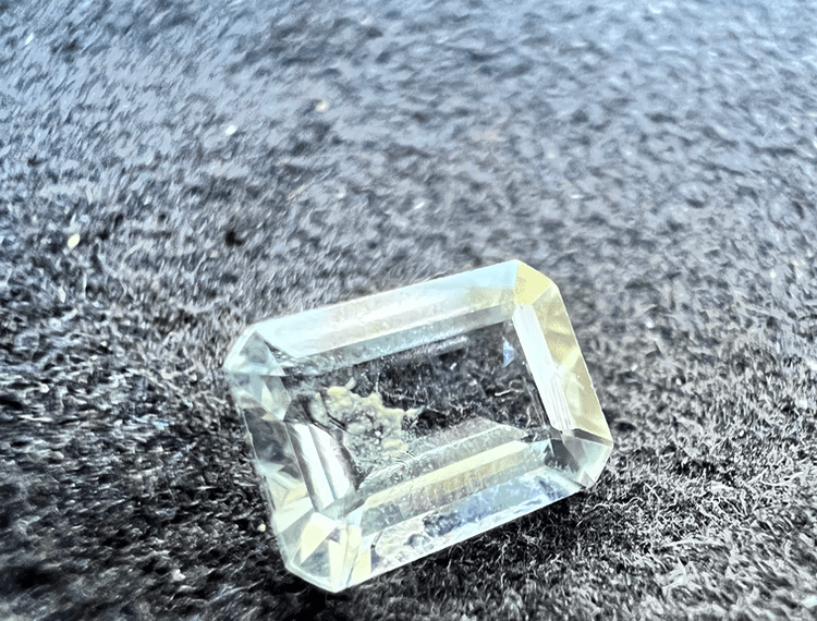 transparent goshenite beryl stone showing an inclusion on a neutral background to illustrate goshenite beryl