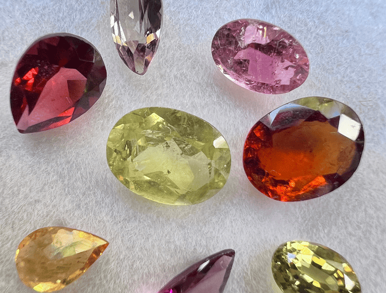 garnet stones assorted with almandine, grossular, rhodolite, spessartite, color change, grandite, malaya and hessonite on white background to illustrate the garnet
