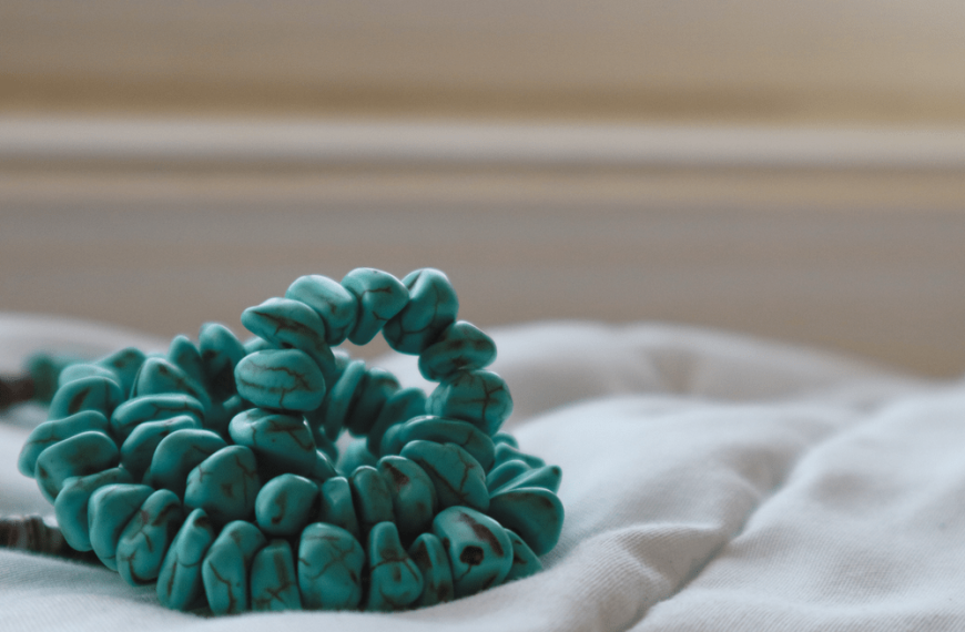 collier de turquoise naturelle enroulé sur un drap blanc pour illustrer la turquoise