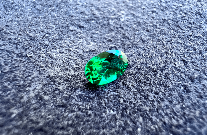synthetic emerald green stone cut on a neutral background to illustrate a green gemstone