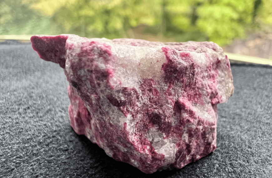pink and white stone of raw thulite on a neutral background to illustrate a pink stone