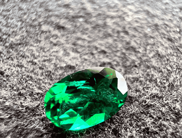 synthetic emerald green stone cut on a neutral background to illustrate a green gemstone